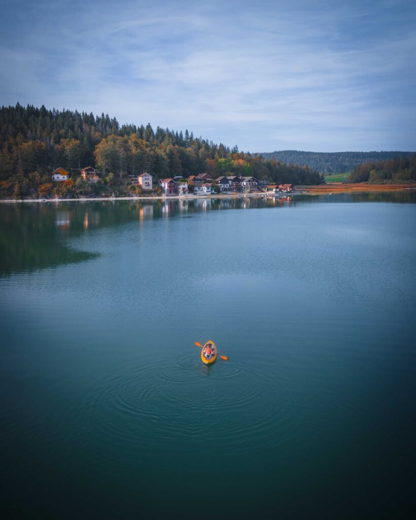 Canoë au milieu d'un lac, des maisons au loin