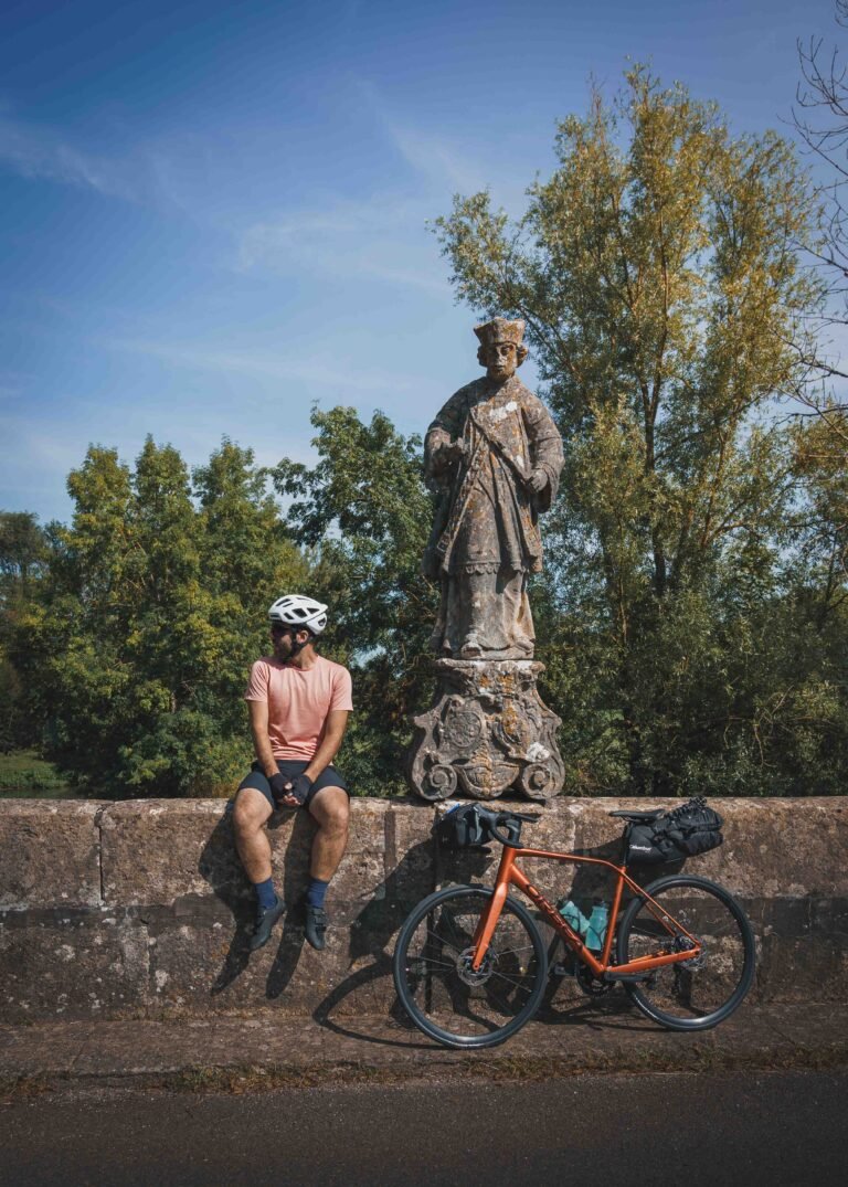 Cycliste faisant un pose au pied d'un statue.