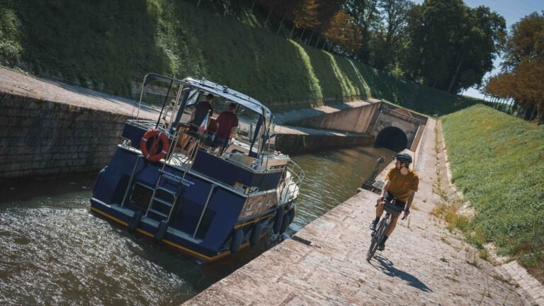 Cycliste au bord d'un canal regardant un bateau.